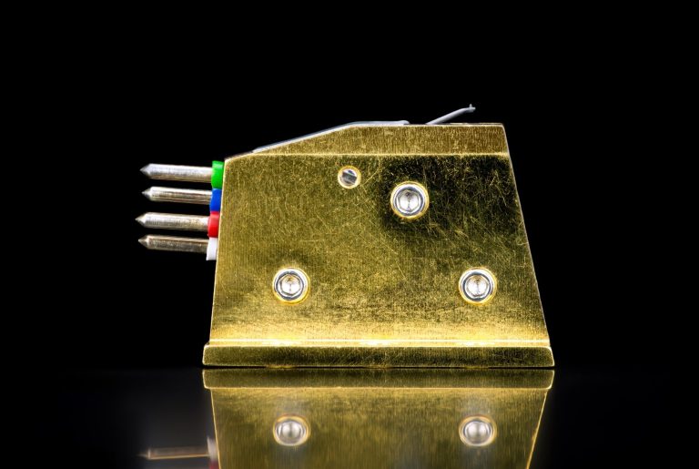 Seitliche Ansicht eines goldenen Audio Note (UK) MC-Tonabnehmers mit drei seitlichen Montageschrauben und vier farbkodierte Kabelanschlüsse
