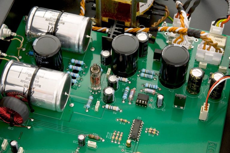 Nahaufnahme des VInnenlebens der Audio Note (UK) DAC 0.1x mit grüne Platinen, Kondensatoren, Widerstände und Kabelverbindungen.