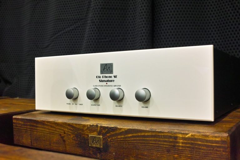 Ein weißer Audioverstärker mit vier Drehreglern auf einem Holzuntergrund.