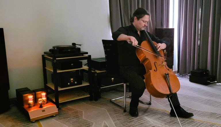 Ein Musiker spielt Cello in einem stilvollen Raum mit Audioequipment von Audio Note.