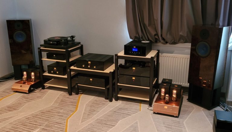 High-End Audioanlage mit Lautsprechern, Verstärkern und Regalen auf einem Teppichboden.