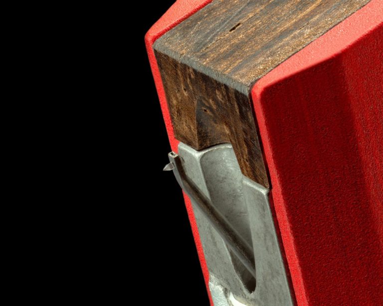 Nahaufnahme einen roten MC-Tonabnehmer mit Nadelträger und Holzdämpfung auf schwarzem Hintergrund.