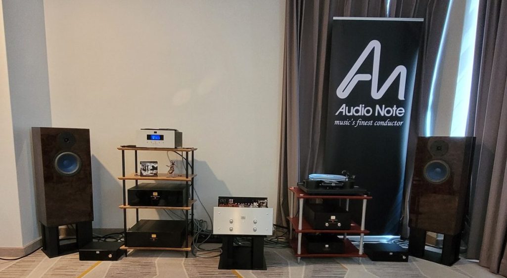 Ein Raum mit Audiogeräte, Plattenspieler, CD-Spieler, Lautsprechern, Verstärker und einem Banner im Hintergrund.